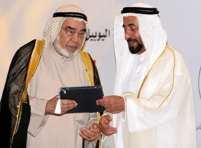 Two men in traditional Arabic attire holding a tablet.