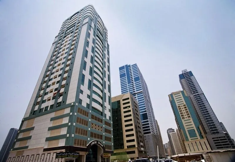 An impressive skyscraper with a vehicle parked in front, highlighting contemporary city design and transportation.