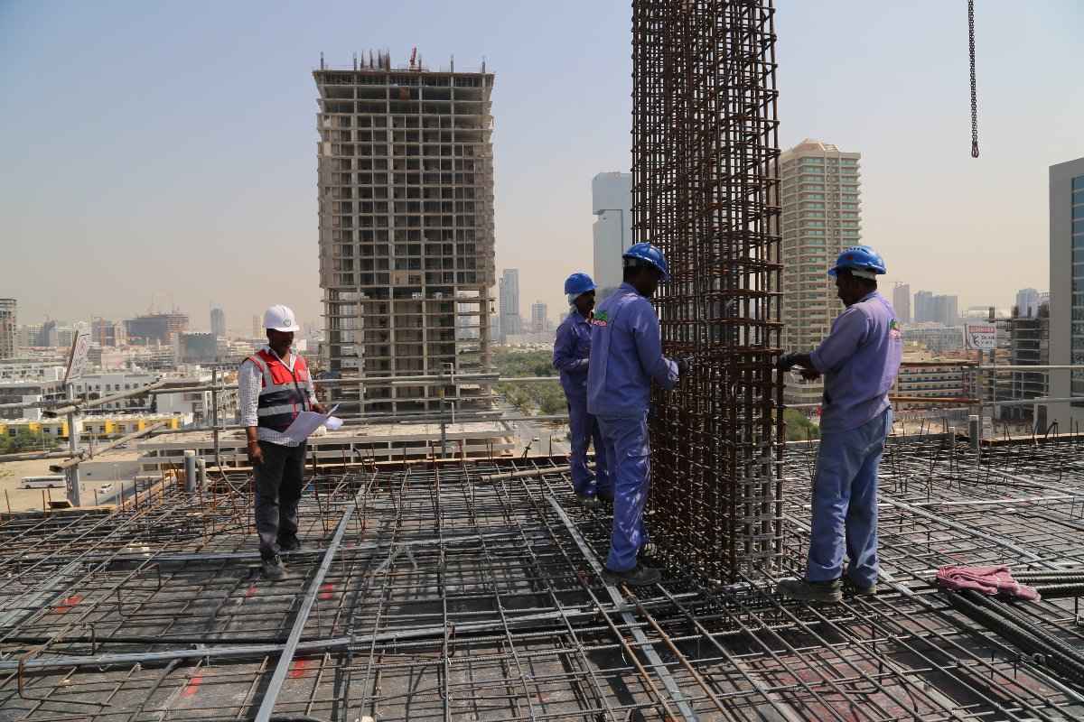 Workers using metal rods to construct a building on a construction site.