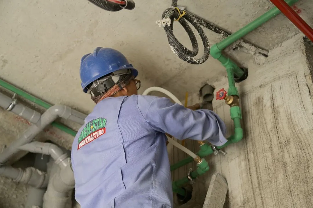 A skilled worker in a hard hat and blue shirt diligently working on a pipe.