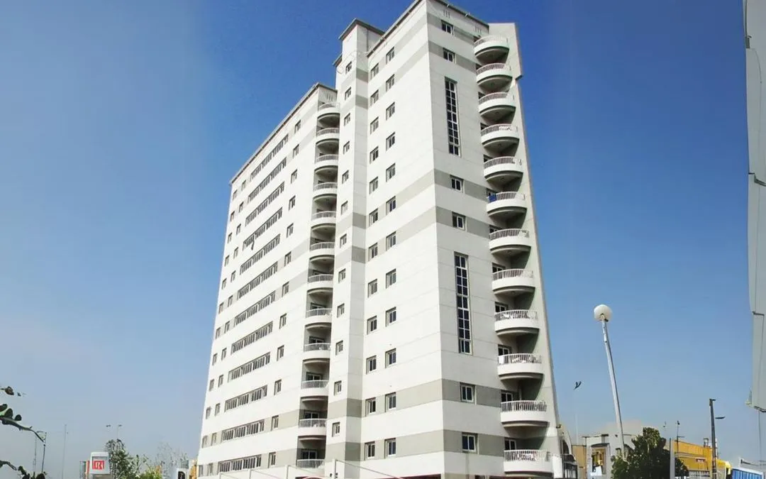 A white high-rise building featuring multiple balconies on each floor.