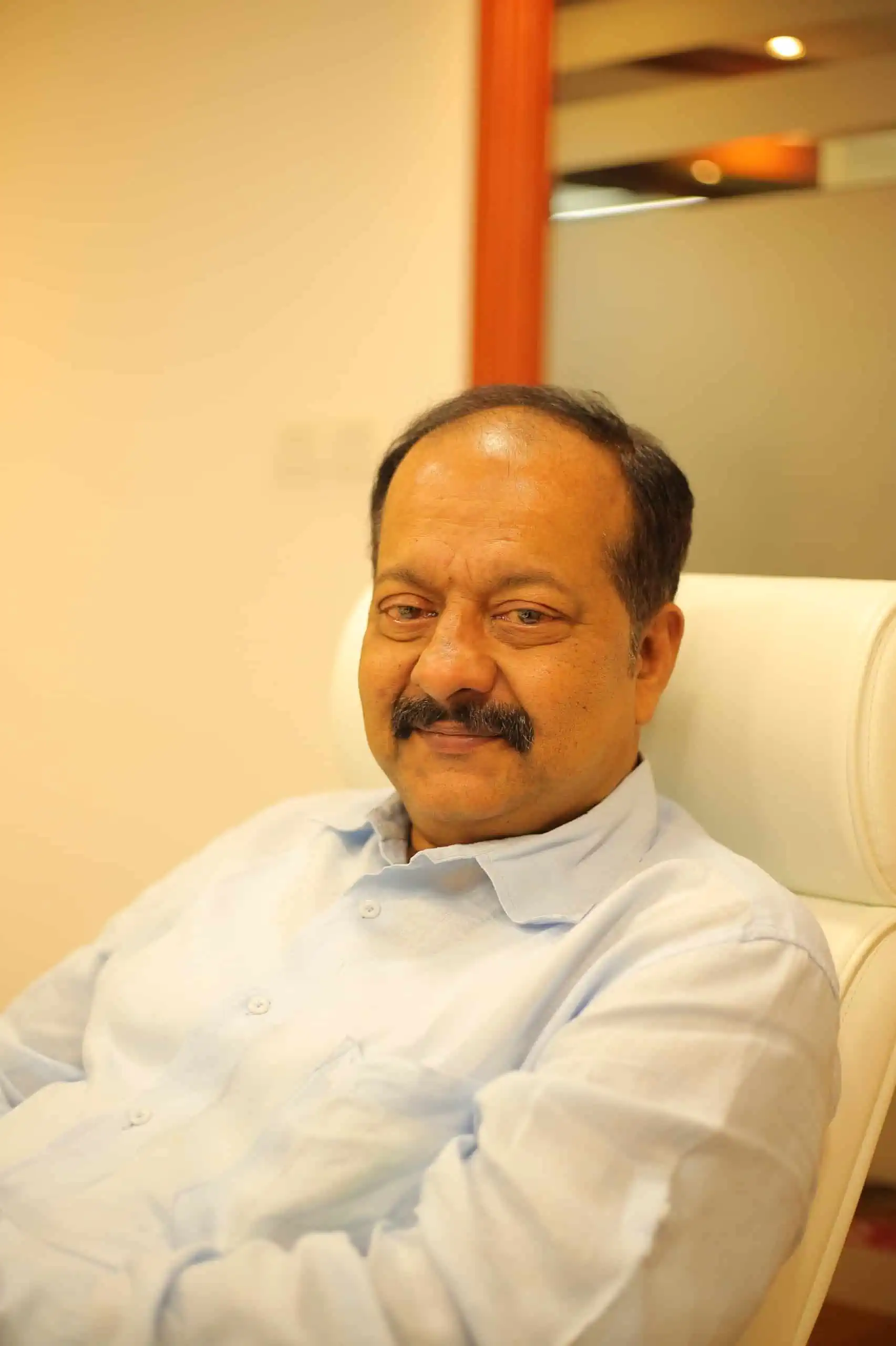 A man sitting in a chair, looking contemplative.