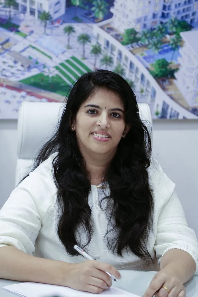 A woman in a white shirt seated at a desk, pen in hand, working diligently.