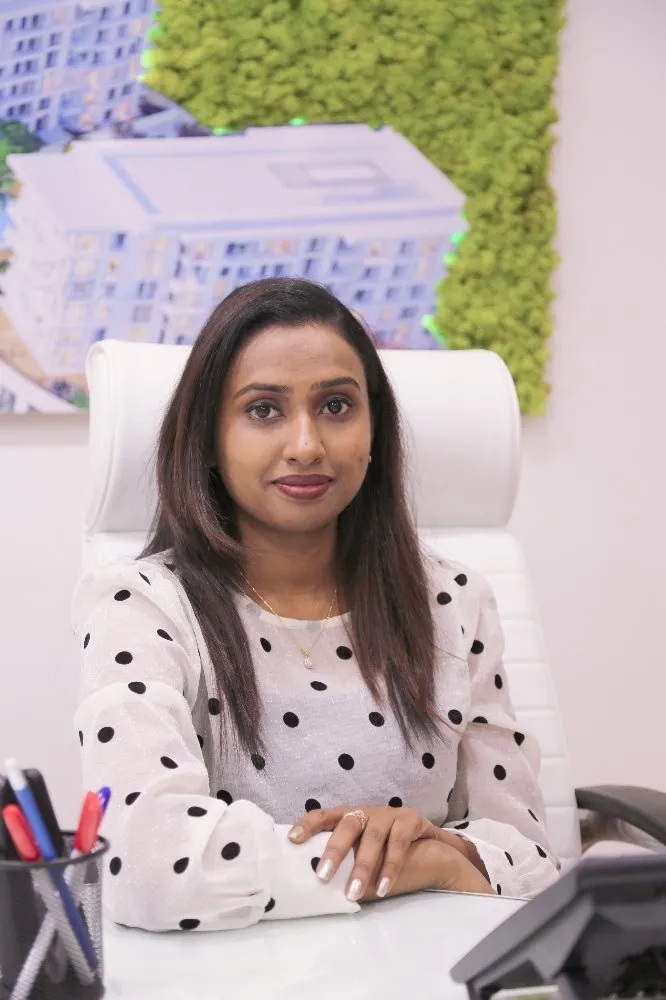 A woman in a polka dot shirt sitting at a desk, focused and engaged in her work.