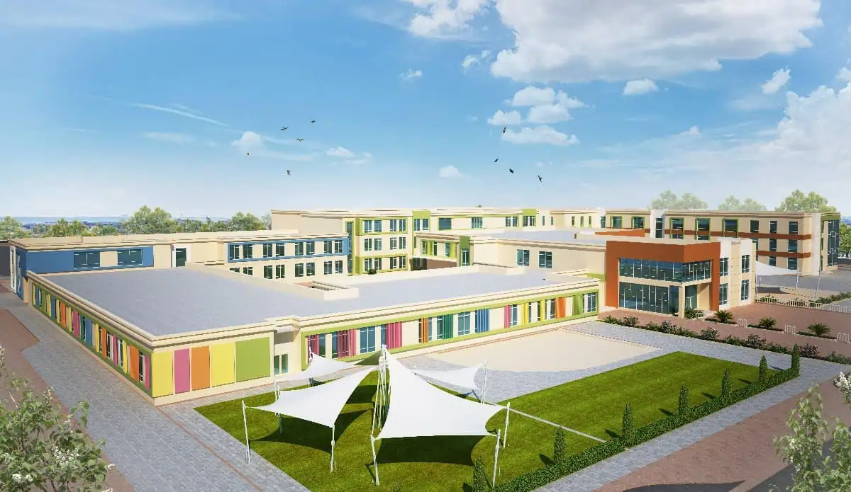 A modern school building with large windows, green spaces, and a playground,