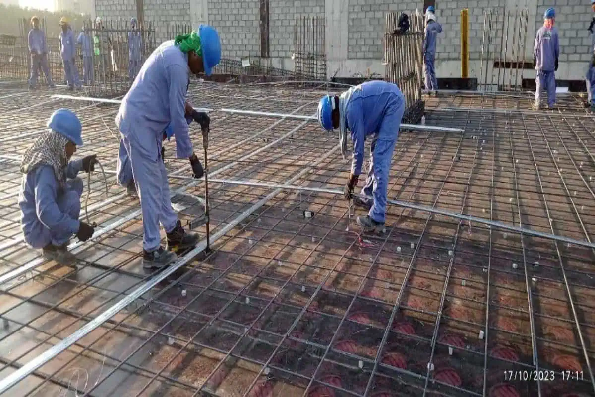 Workers using metal rods to construct a building on a construction site.