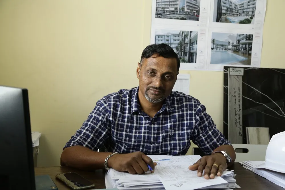 A man sitting at a desk with papers and a computer, working diligently.