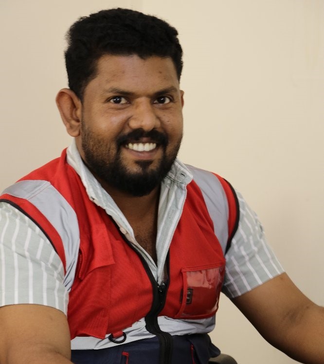 A man in a red and white vest smiling, radiating joy and positivity.