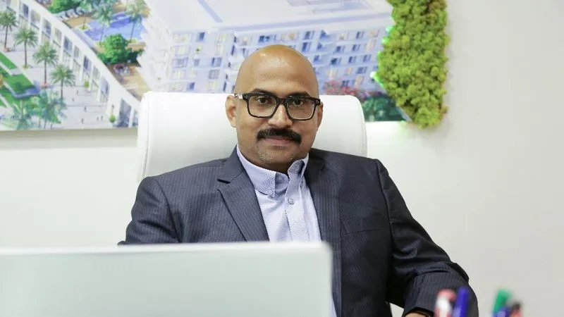 A man in a suit sitting at a desk with a laptop, focused on work.