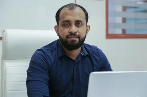 A bearded man focused on his laptop screen, working diligently.