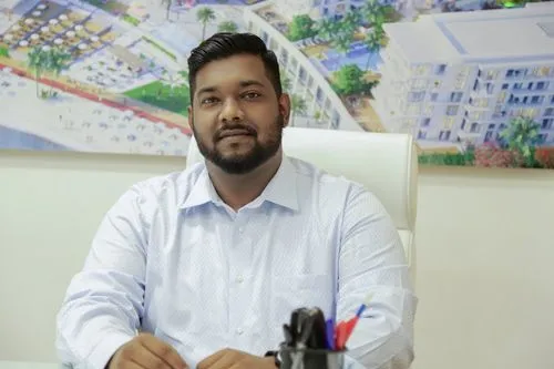 A focused man in a blue shirt sitting at a desk, engrossed in his work.